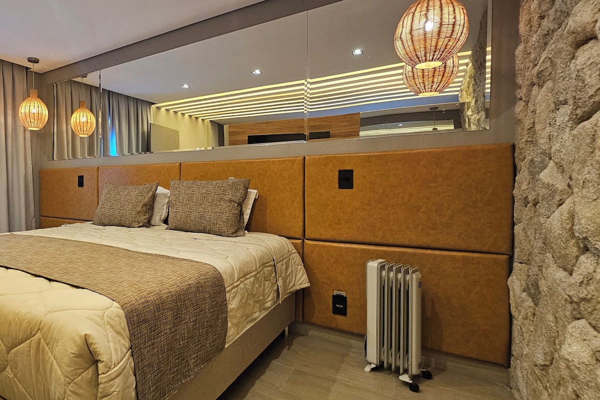 A modern bedroom with a large bed, a mirror, and a radiator.