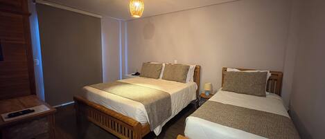 A bedroom with two single beds, a wooden wardrobe, a heater, and a hanging light fixture.