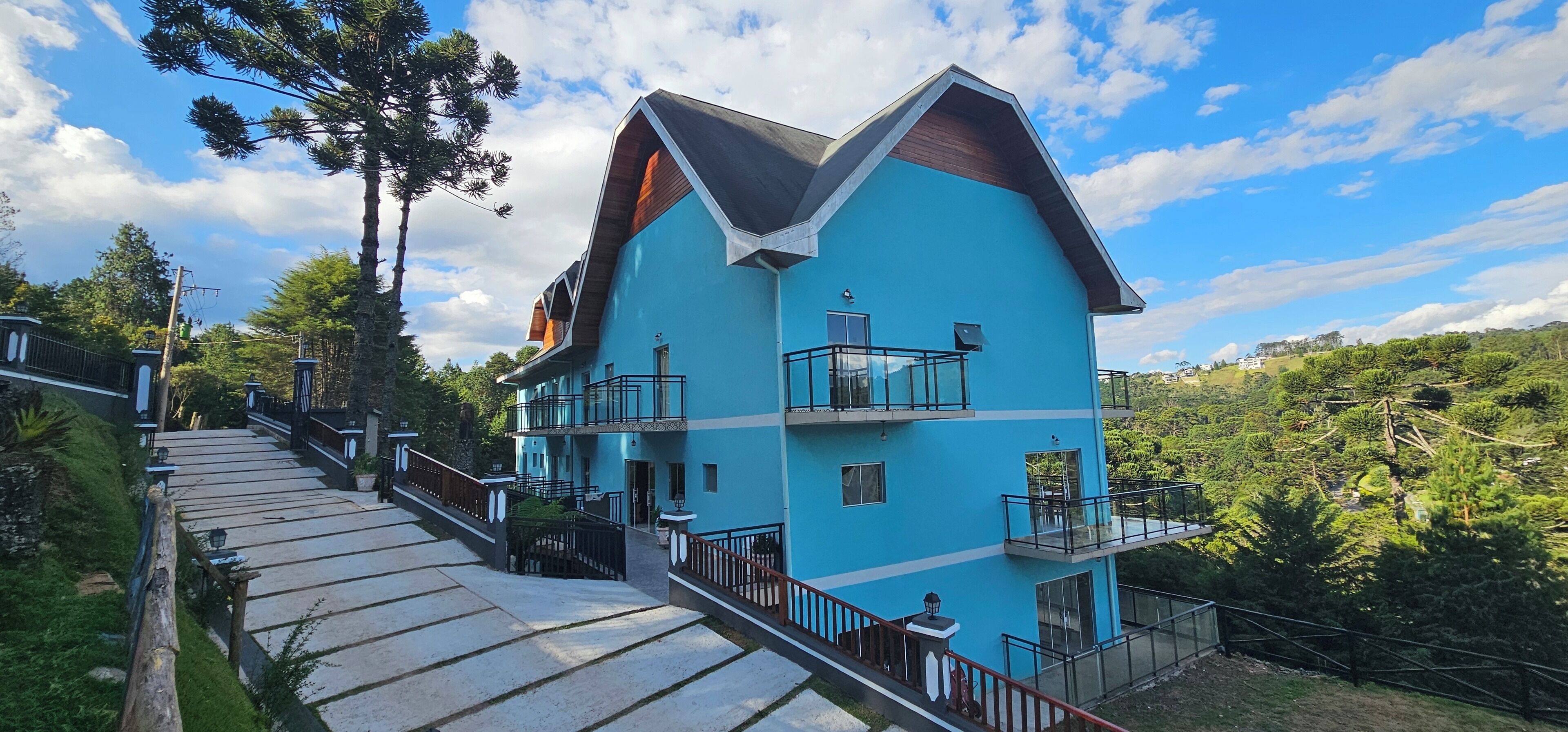 A multi-story building with a blue exterior, a wooden sloped roof, and balconies.