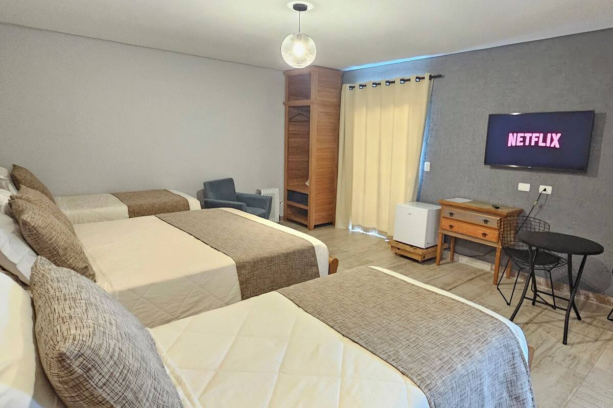 A hotel room with two beds, a desk, a chair, a TV, and a wardrobe.