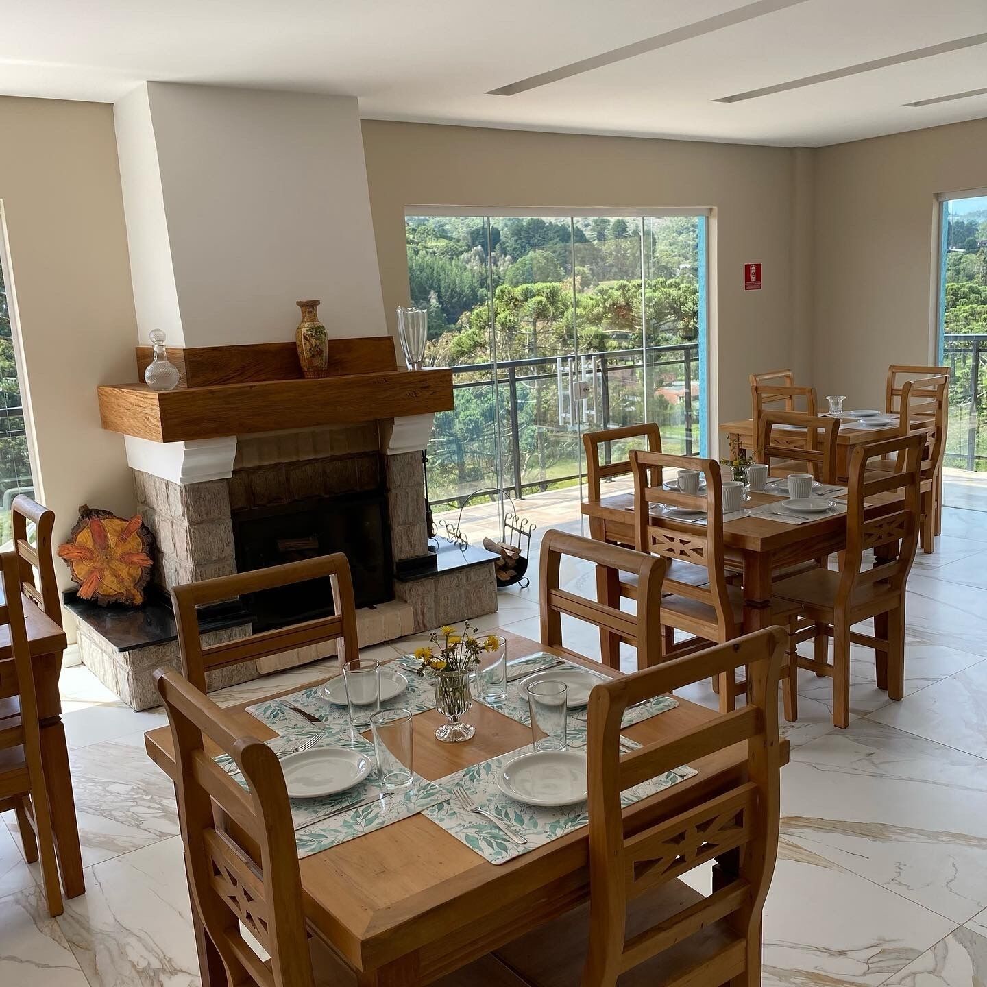 A dining area with a fireplace, wooden chairs, and a table set for four.