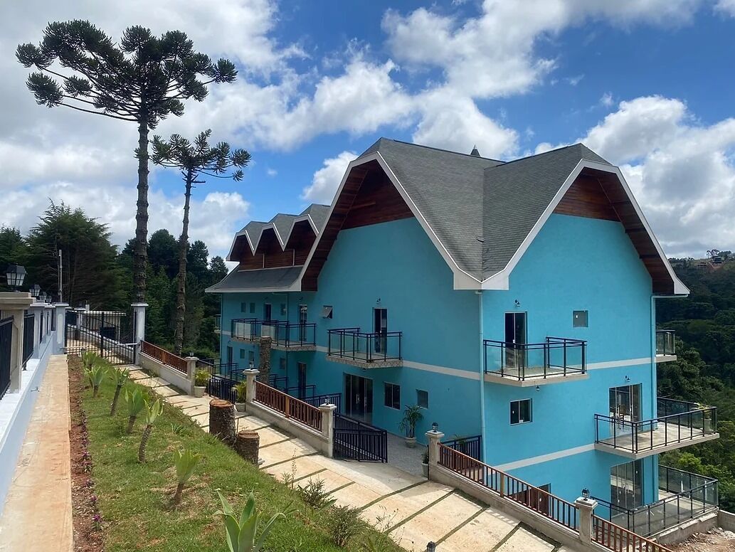 A multi-story building with a blue exterior, multiple balconies, and a sloped roof.