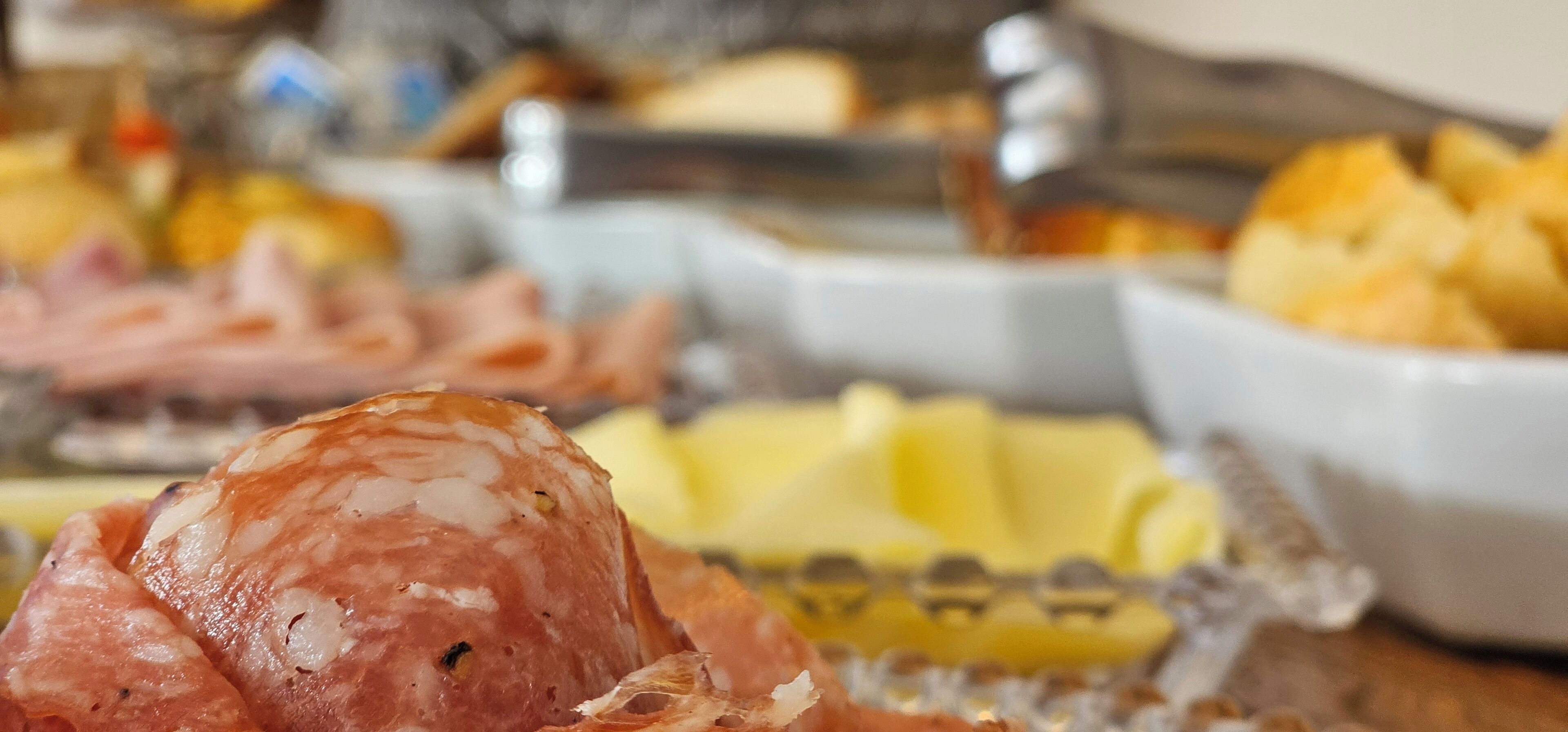 Buffet con diversos alimentos, incluyendo embutidos y queso.