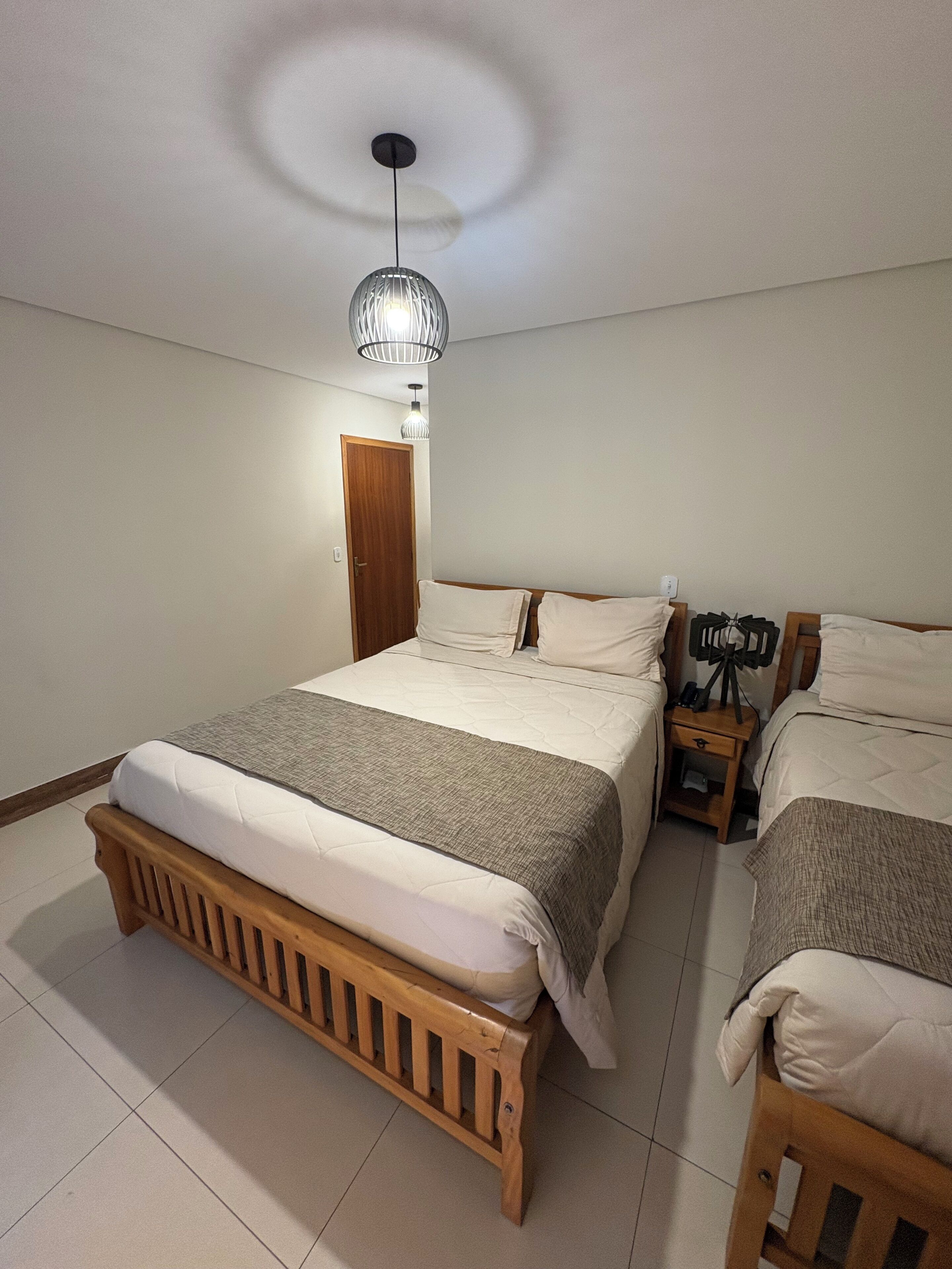Quarto com uma cama grande, uma mesa de cabeceira e um candeeiro.
