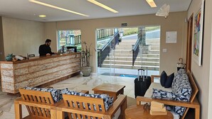 Zona de recepción con recepcionista, mostrador, escalera que da al exterior y disposición de asientos.