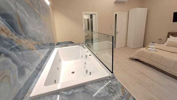 Un bagno moderno con un vanità in marmo, una vasca da bagno con chiusura in vetro e una doccia a filo pavimento.