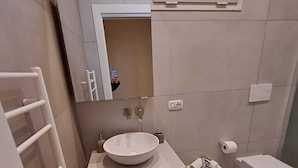 Un bagno moderno con uno specchio grande, un lavandino, un bidet e un water.
