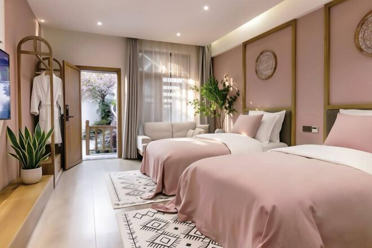 A modern hotel room with two beds, a TV, a plant, and a balcony with a view.