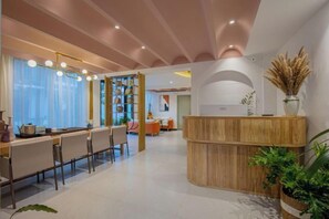 A modern hotel lobby with a reception desk, seating area, and a large window. - The Valley of Flowers (Lijiang)
