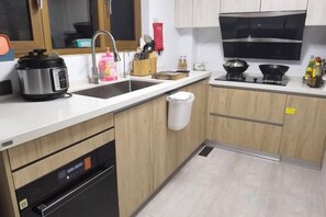 A compact kitchen with a dishwasher, a sink, a stove, and a microwave. - The Valley of Flowers (Lijiang)