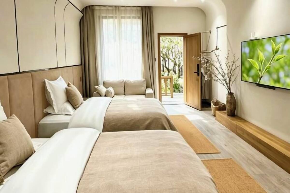 A hotel room with a large bed, a smaller bed, a TV, and a view of the outdoors.