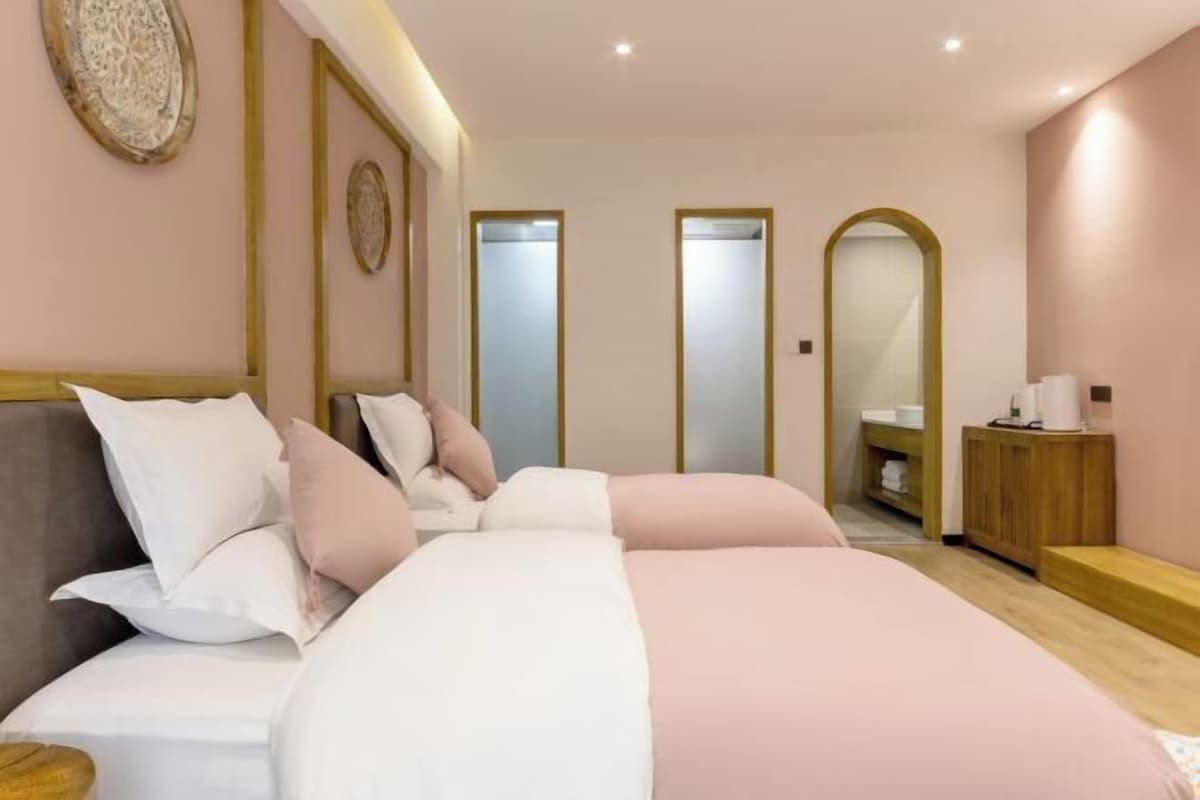 A bedroom with a bed, bedside tables, a mirror, a wardrobe, and a bathroom with a sink and mirror.