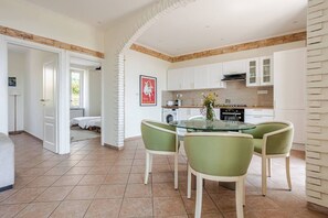 Uma cozinha moderna com armários brancos, uma mesa de jantar de vidro e cadeiras verdes.