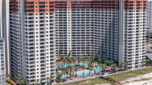 A high-rise hotel with multiple balconies, a swimming pool, and a beach area with sun loungers. - Direct Beachfront, Wrap Balcony, Breathtaking Views! Shores of Panama (Panama City Beach)