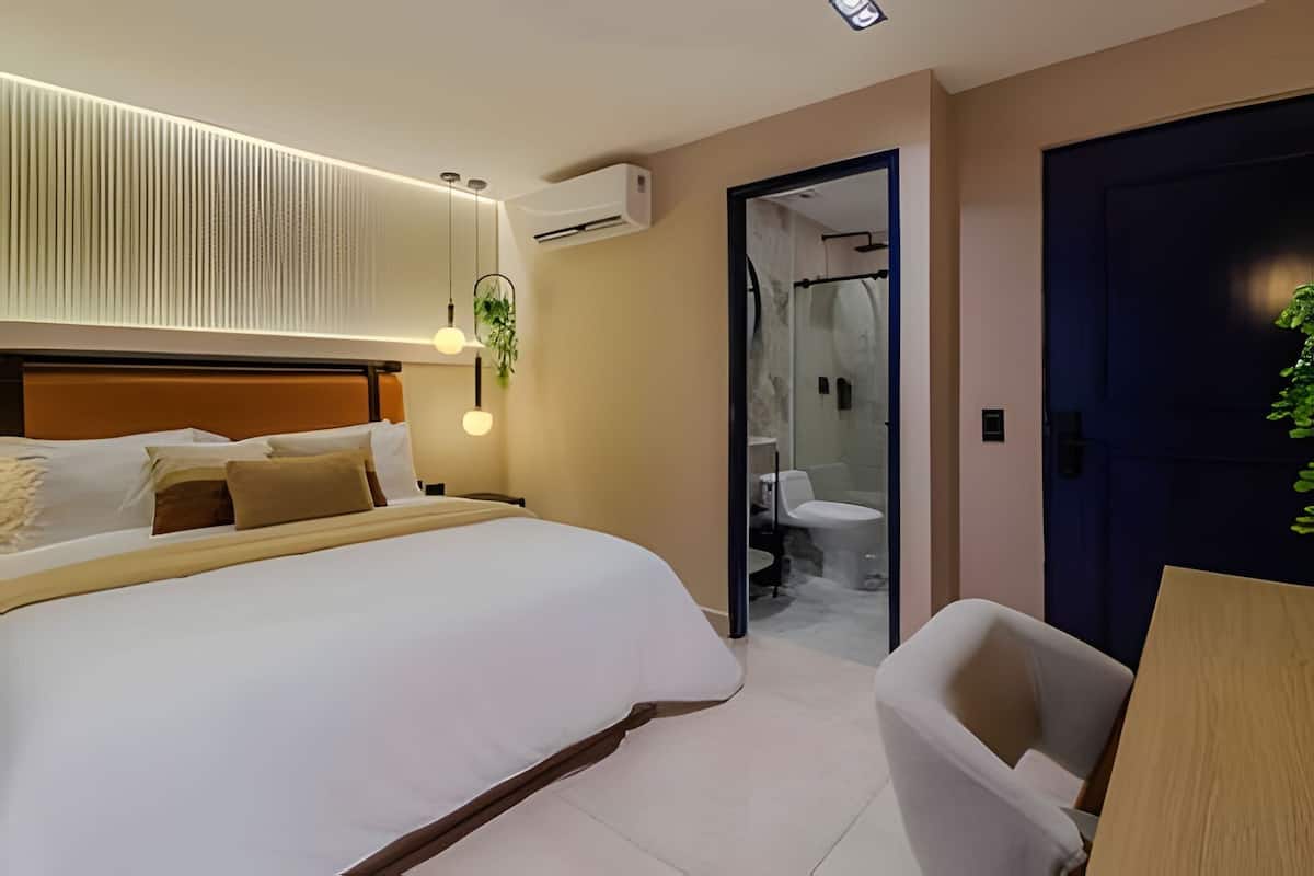 A modern hotel room with a large bed, bedside table, and a shower area.