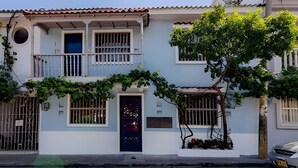 A two-story building with a balcony, a door, and a window with bars. - Serrezuela Rooms (Cartagena)