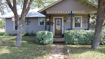 A single-story house with a front porch, a small garden, and a pathway leading to the door.