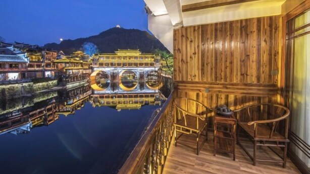 Un balcón de madera tradicional con vista a una masa de agua y el reflejo de edificios.