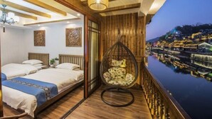 Una habitación de hotel con una cama, una silla colgante y vistas a un cuerpo de agua con edificios.
