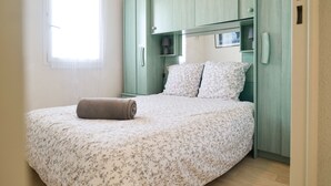 Un dormitorio con cama, ventana y un armario verde.