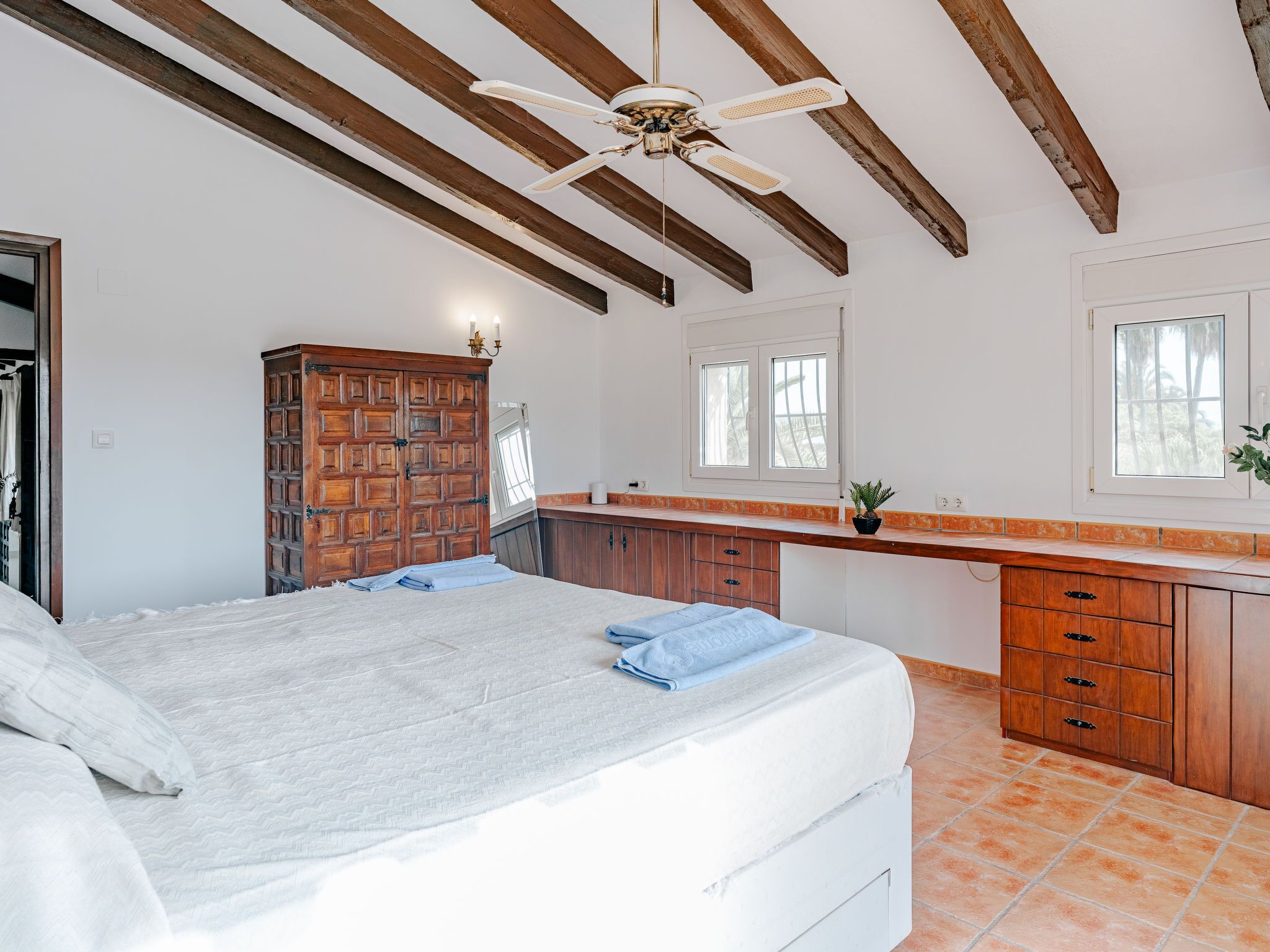 Ein Schlafzimmer mit einem Bett, einem Holzschrank und einem Deckenventilator.