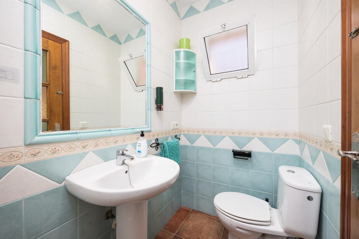 Une salle de bain équipée d’un lavabo, de toilettes, d’un miroir et d’un porte-serviettes.
