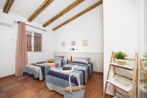 Een slaapkamer met twee bedden, een raam met tralies, een plank met een plant en een ladder.