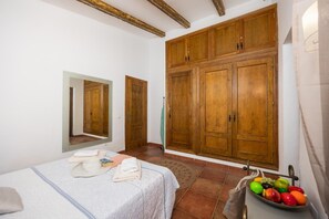 Une chambre à coucher avec un lit, une grande armoire, un miroir et un panier de fruits.