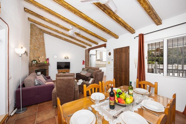 A living room with a sofa, TV, and dining table set for a meal. - Villa Maria Gomez - Three Bedroom Villa, Sleeps 6 (Frigiliana)