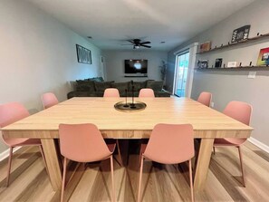 Un coin repas avec une table en bois et six chaises roses.