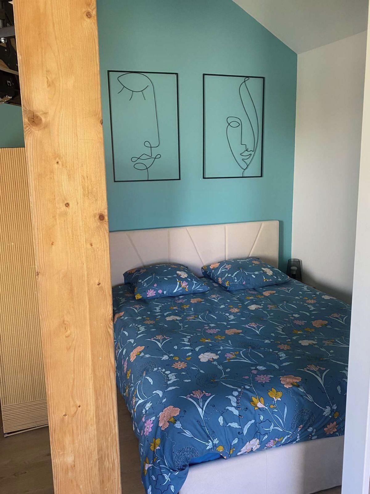 A bedroom with a bed, a headboard, and two wall art pieces.