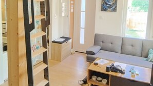 Una sala de estar moderna con una escalera de madera, un sofá gris, una mesa de centro y un cuadro en la pared.