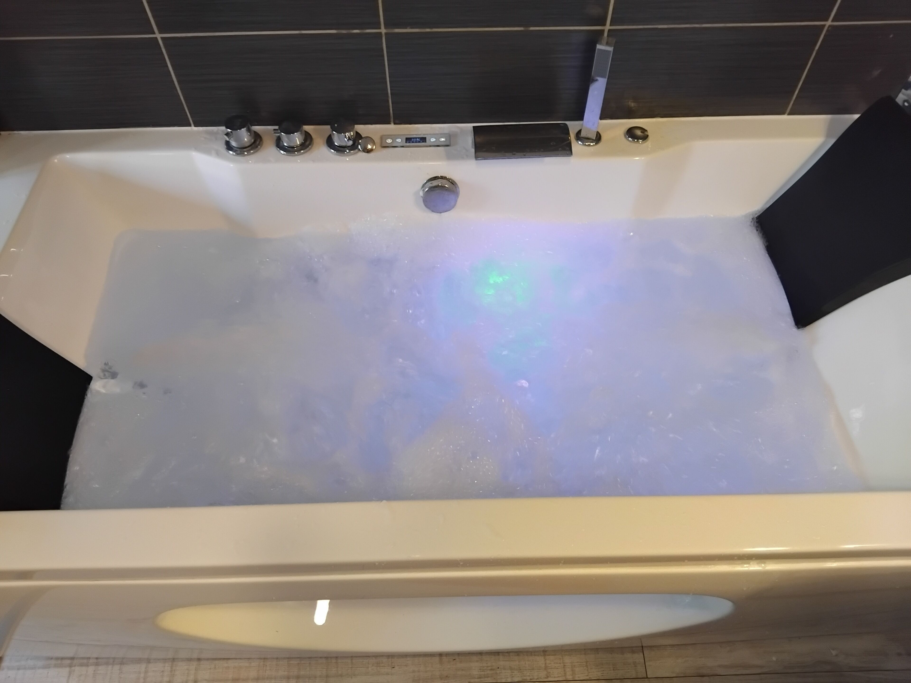 Une baignoire dotée de plusieurs commandes, d’un drain et d’un indicateur de niveau d’eau visible.