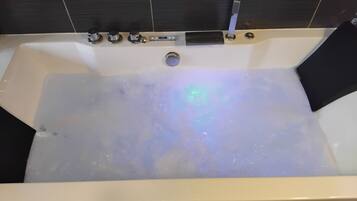 Une baignoire dotée de plusieurs commandes, d’un drain et d’un indicateur de niveau d’eau visible.