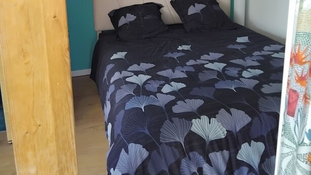 Un dormitorio con una cama, dos obras de arte en la pared y suelo de madera.