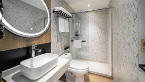 Een moderne badkamer met een vrijstaand badkamermeubel, toilet en douchecabine met glazen wanden.