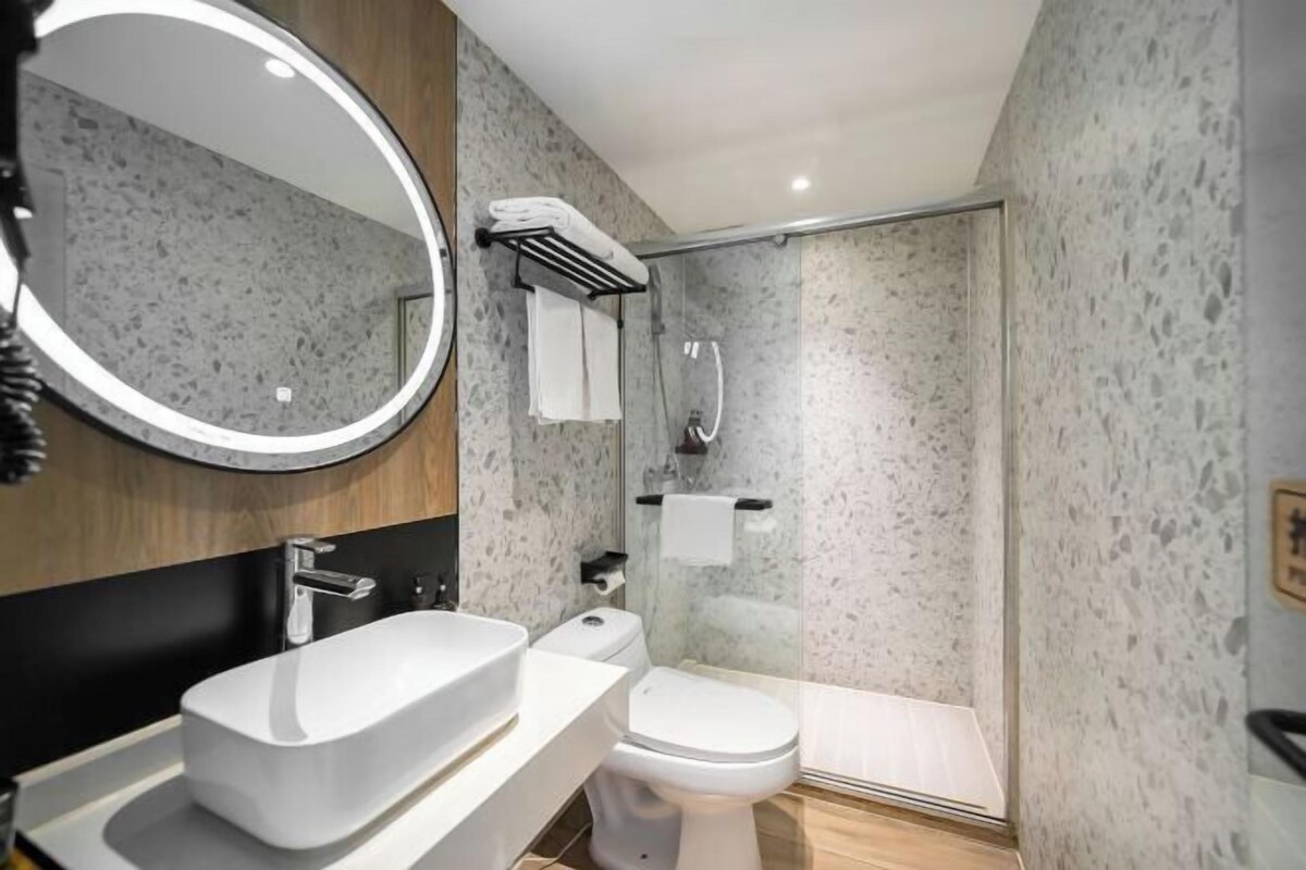 Een moderne badkamer met een vrijstaand badkamermeubel, toilet en douchecabine met glazen wanden.