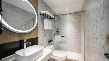 Un baño moderno con lavamanos independiente, inodoro y ducha con mampara de vidrio.