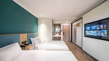 Habitación de hotel con dos camas, un televisor, un espejo y un baño a la vista.