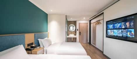Une chambre d’hôtel avec deux lits, une télévision, un miroir et une salle de bain que l’on aperçoit à l’arrière-plan.