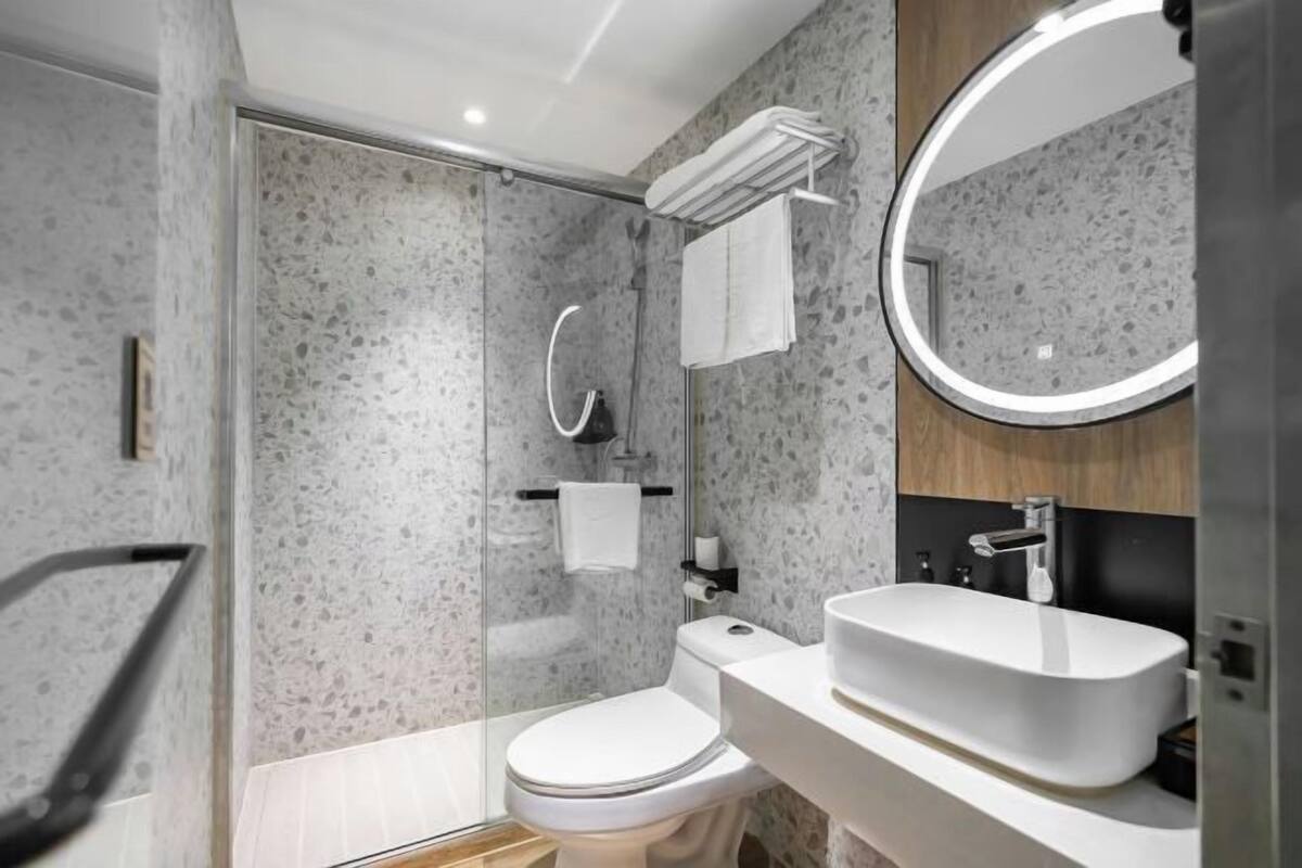 A modern bathroom with a shower, toilet, and sink, featuring a speckled wall design.