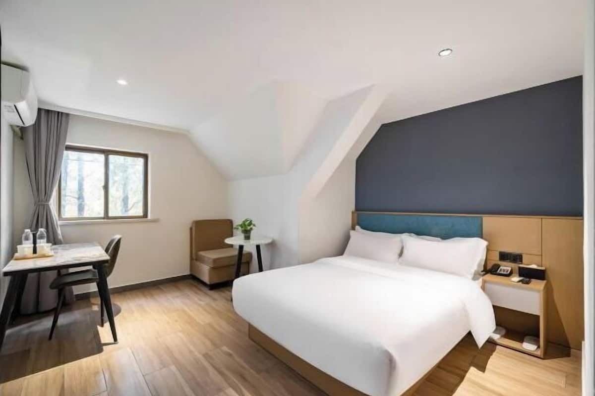 A modern hotel room with a large bed, a desk, and a small table.
