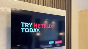 Un televisor de pantalla plana montado en una pared con paneles de madera, mostrando un mensaje promocional de Netflix.