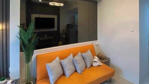 Una sala de estar moderna con un sofá, un espejo grande, una lámpara de araña y una planta en maceta.