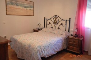 Ein Schlafzimmer mit Bett, Nachttisch, Kommode und einem Bild an der Wand.
