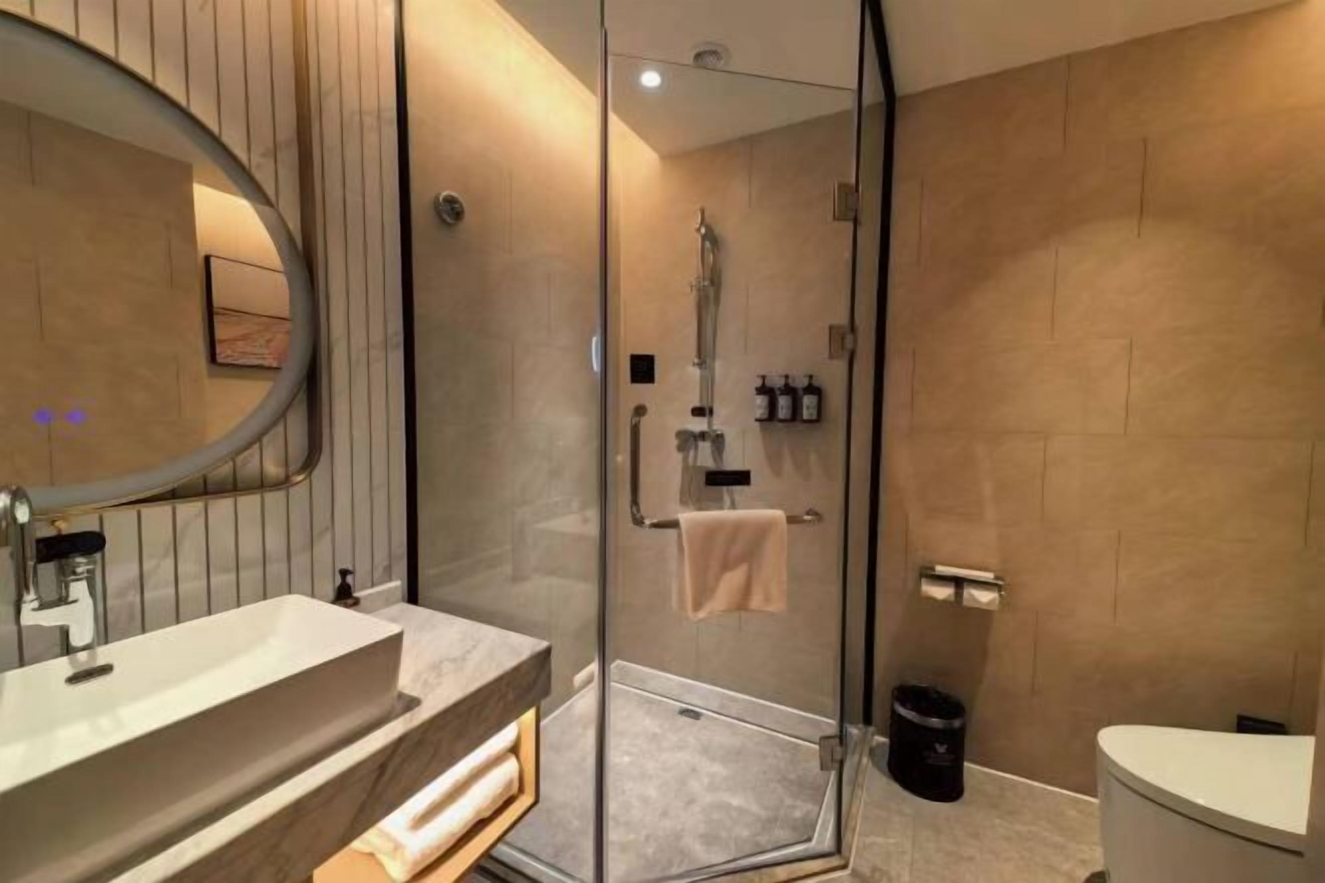 A modern bathroom with a glass-enclosed shower, a sink with a mirror, and a toilet.