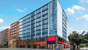 A modern building with a glass facade, multiple floors, and a mix of commercial spaces on the ground level. - Vienna International Hotel(ShenzhenLuohu Shuibei Jewelry City Branch) (Shenzhen)