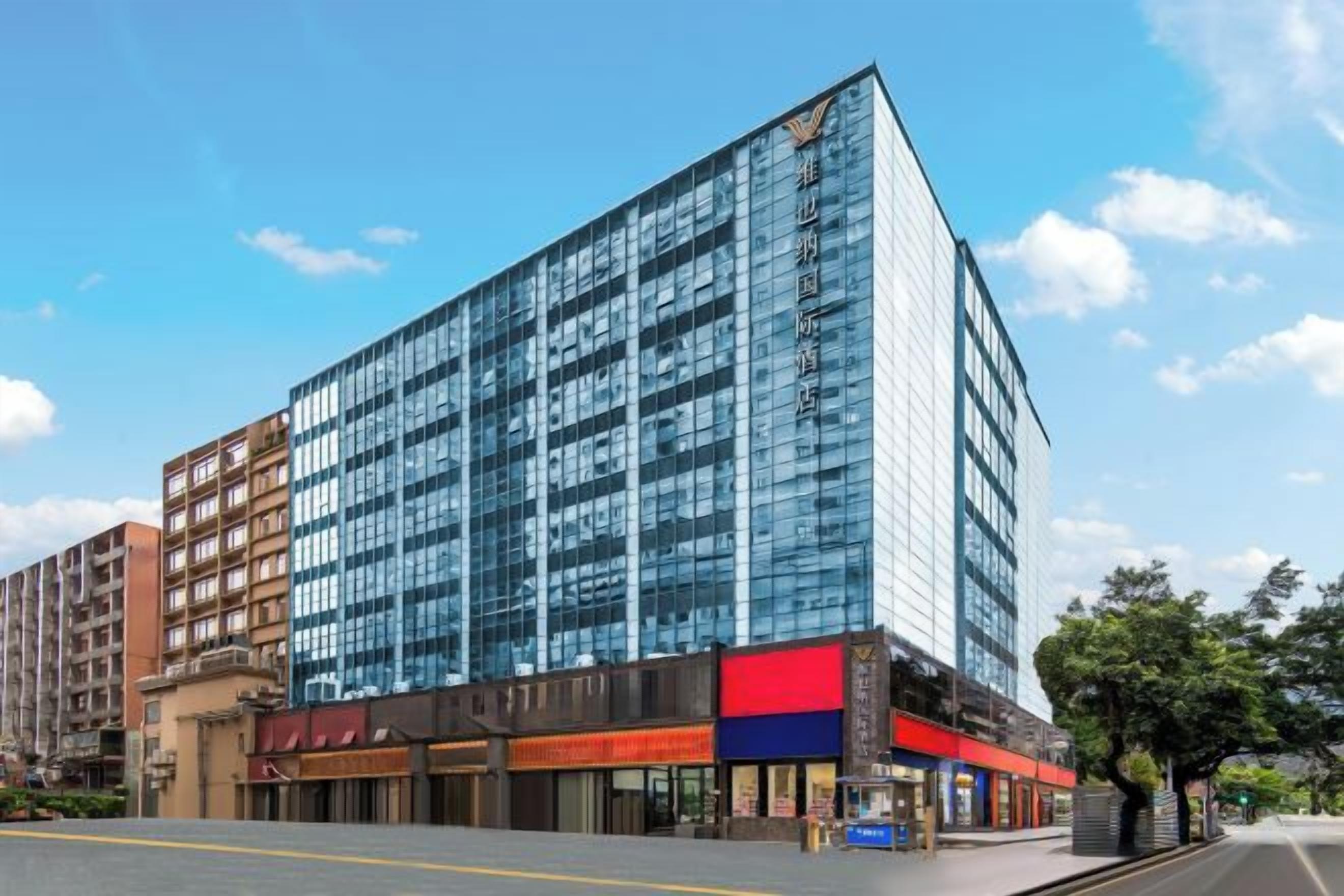 A modern building with a glass facade, multiple floors, and a ground-level commercial area with shops.