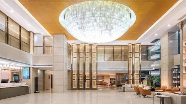 A spacious lobby with a large chandelier, a reception desk, seating area, and a staircase. - Vienna International Hotel(ShenzhenLuohu Shuibei Jewelry City Branch) (Shenzhen)