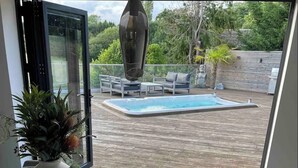 A dining area with a table, chairs, and a view of a swimming pool and garden. - Branksome 4-house Sleeps 8 With Hot Tub & Parking (Worcester)